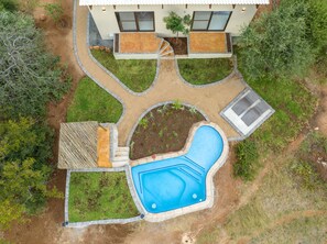Vista aérea de uma casa com piscina, rodeada por um jardim bem cuidado com um caminho de pedra.