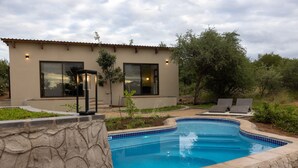 Une maison moderne dotée d’une piscine, de grandes fenêtres et d’un espace salon extérieur.