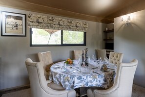 Un coin repas avec une table ronde dressée pour quatre personnes, entourée de chaises rembourrées.