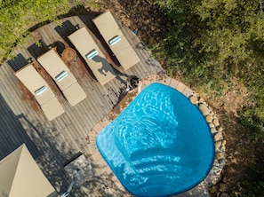 Vista aérea de una piscina con sillas de descanso y una terraza.