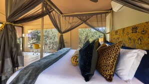 A bedroom with a bed, canopy, and a view of the outdoors. - Canvas Villa with pool (Hoedspruit)