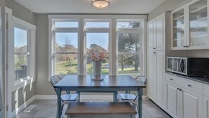 A kitchen with a dining table, chairs, a vase with flowers, and cabinets. - The Cottage @ Afton Mountain- Close to Wineries! (Afton)