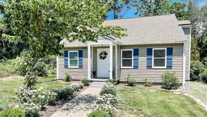 A single-story house with a front porch, a pathway leading to the door, and a small garden with various plants and flowers. - The Cottage @ Afton Mountain- Close to Wineries! (Afton)