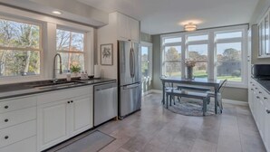 A modern kitchen with white cabinets, stainless steel appliances, and large windows offering views of the outdoors. - The Cottage @ Afton Mountain- Close to Wineries! (Afton)