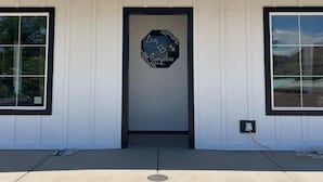 Un edificio con fachada blanca, una puerta negra y un letrero en la puerta que dice 'Lazy Bungalow'.