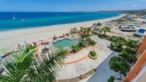 Un complexe hôtelier situé sur la plage, doté d’une piscine, de chaises longues et de bateaux.