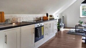 Une cuisine moderne avec des meubles blancs, un plan de travail noir et un four encastré.