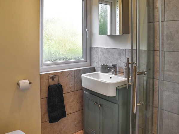 A bathroom with a window, a sink, a mirror, and a towel rack.