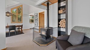Ein modernes Wohnzimmer mit Kamin, einem Essbereich mit Tisch und Stühlen sowie einer gemütlichen Sitzecke mit einer Couch.