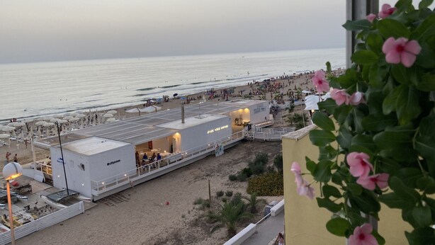 A beachside view with a restaurant and a bar area, including outdoor seating and umbrellas. - Terrace overlooking the sea (Scoglitti)