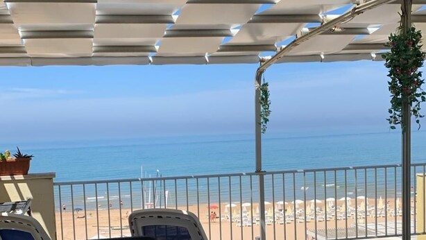 A covered outdoor seating area with a view of the beach and ocean. - Terrace overlooking the sea (Scoglitti)