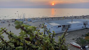 A beach with boats, umbrellas, and a building with a sign. - Terrace overlooking the sea (Scoglitti)