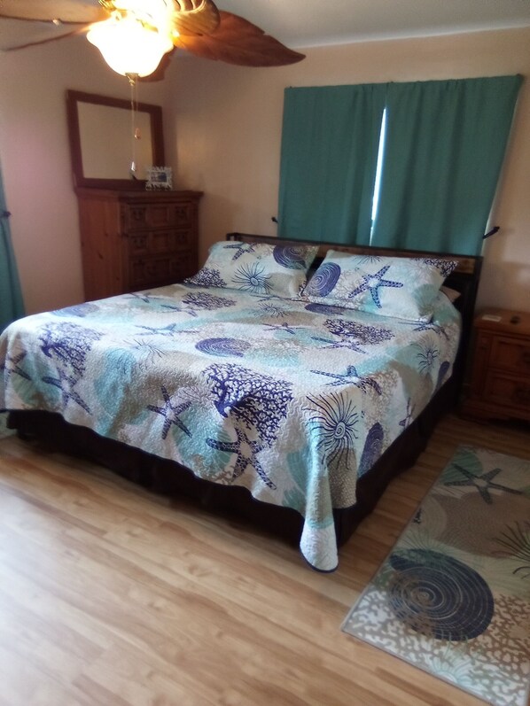 Une chambre à coucher avec un lit, une commode en bois et un ventilateur de plafond.
