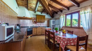 A kitchen with wooden cabinets, a dining table with chairs, and a window with curtains. - XIM ( Angels ). Nice villa within walking distanace to Pollensa (Pollensa)