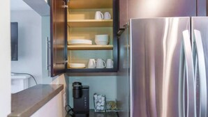 A compact kitchen with a built-in coffee maker, a refrigerator, and shelves for dishes and cups. - Sunny Retreat Haven (Minneapolis)