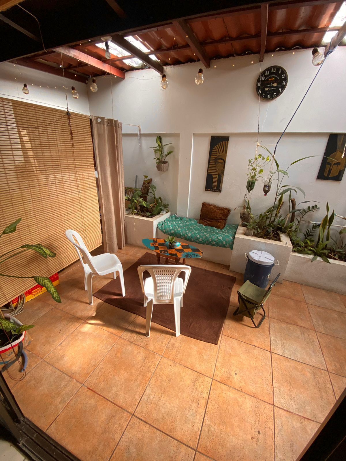 Un patio acogedor con techo de madera, un reloj y varias plantas en macetas.