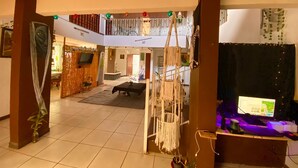 Ein geräumiger Wohnbereich mit Balkon, einem Flachbildfernseher, einem Gaming-Setup und einer Treppe.
