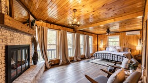 A log cabin interior with a fireplace, a bed, and a seating area.
