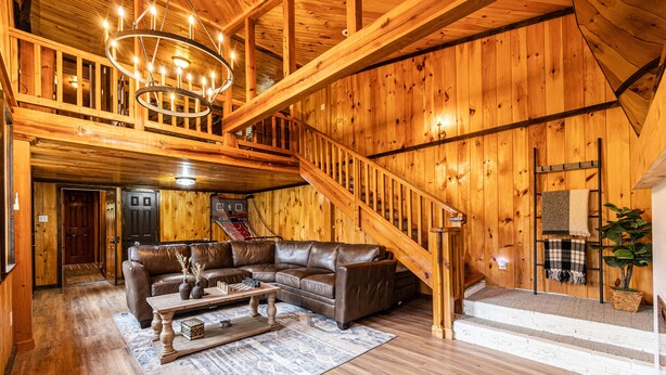 A spacious living room with a brown leather sofa, a wooden coffee table, and a staircase leading to an upper level.