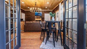 A wooden interior with a dining area, a sofa, and a painting on the wall.