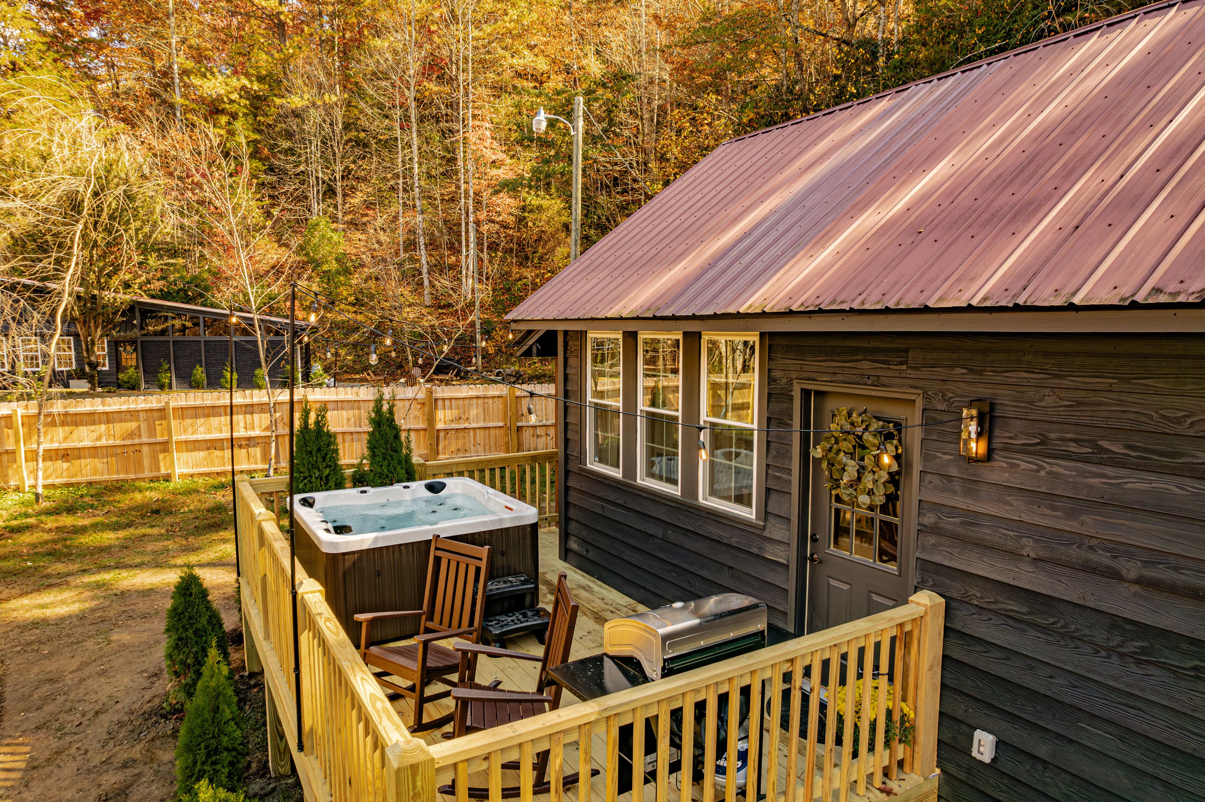A wooden cabin with a hot tub, deck, and a garage.