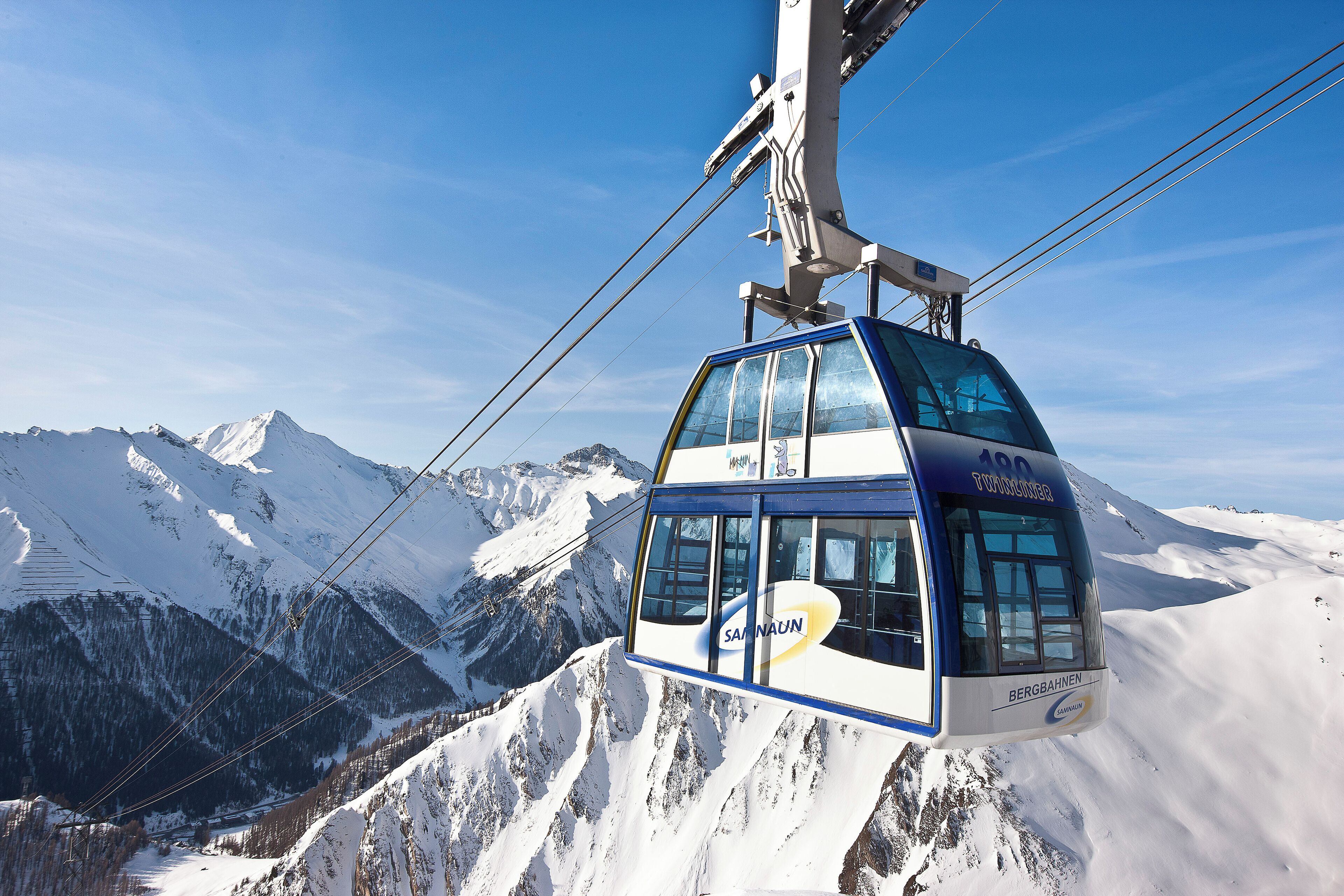 Un teleférico ofrece vistas despejadas de montañas nevadas y un cielo azul.