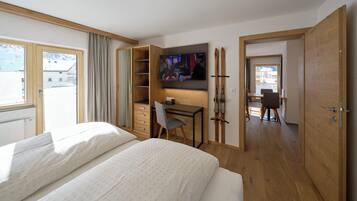 A hotel room with a bed, a desk with a chair, a TV, and a ski rack.