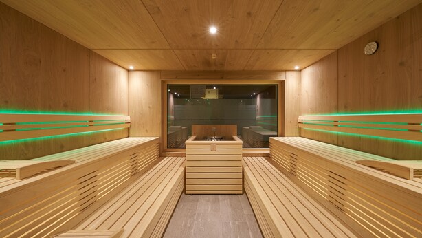 A sauna with wooden benches and a central bench with a sink.