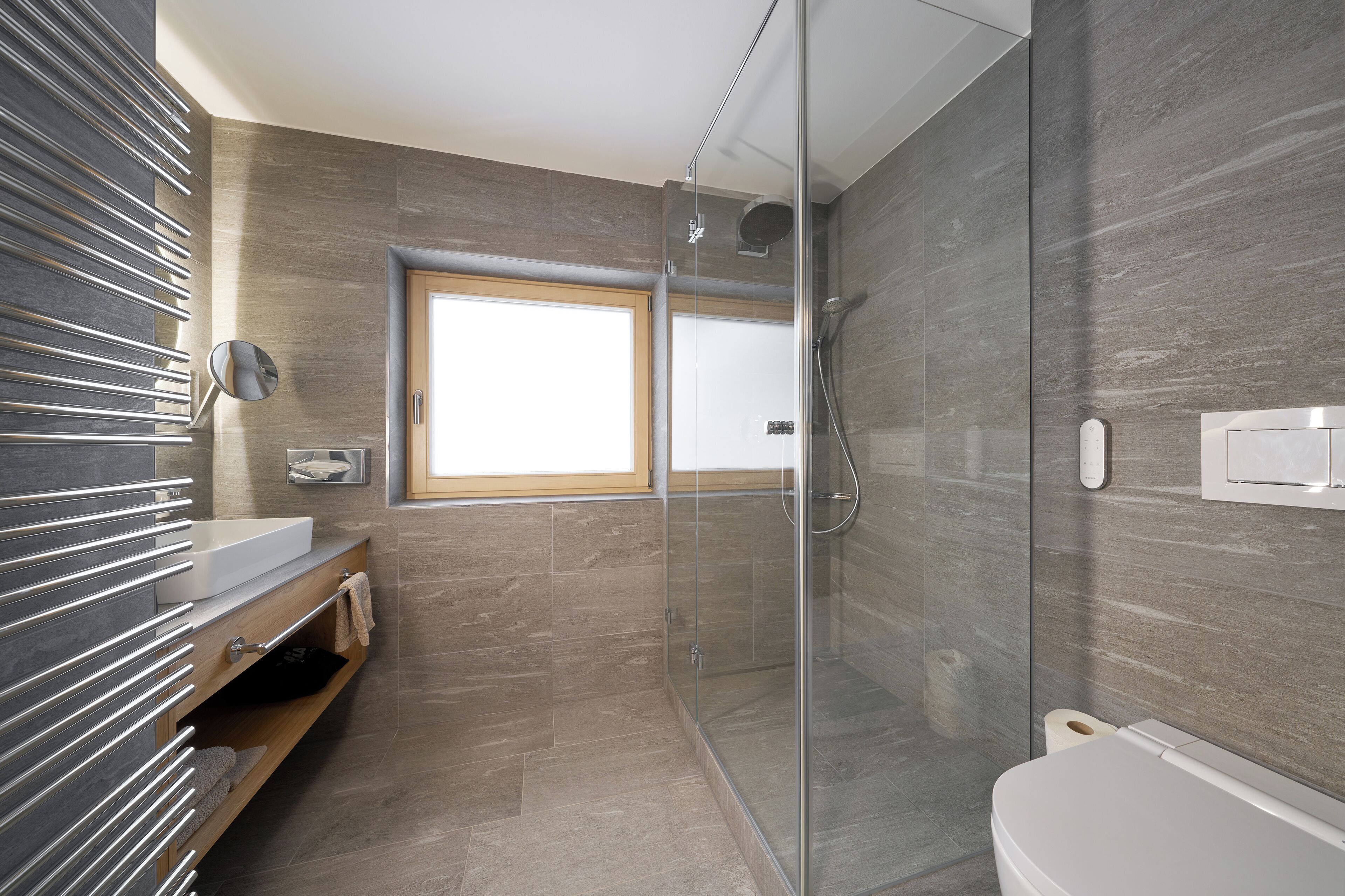 A modern bathroom with a glass-enclosed shower, a wooden vanity with a mirror, and a toilet.