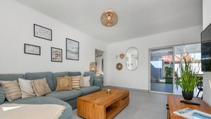 Un salon moderne avec un canapé gris, une table basse en bois et une grande fenêtre donnant sur l’extérieur.
