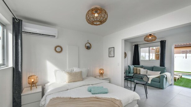 Une chambre moderne avec un grand lit, des lampes de chevet, un canapé et une vue sur l’extérieur.