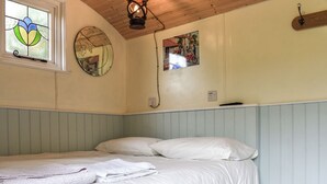 Un dormitorio con cama, una ventana con diseño de vitral, un reloj de pared y una lámpara fijada a la pared.