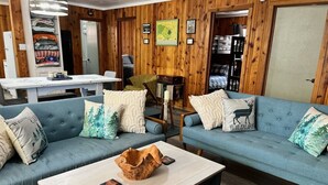 A cozy living room with two blue sofas, a coffee table, and a wooden wall. - Alpine Dog Friendly Cabin! (Alpine)