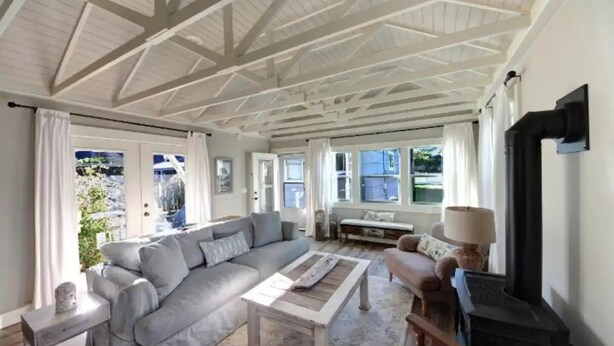 A spacious living room with a high ceiling, a large grey sofa, a coffee table, and a fireplace. - LaVerna! LaVerna! (Ocean Park)