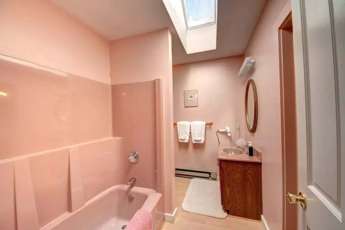 A bathroom with a bathtub, a vanity with a mirror, and a towel rack.