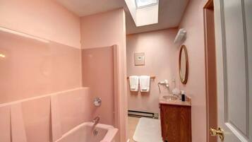 A bathroom with a bathtub, a vanity with a mirror, and a towel rack.