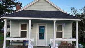 A single-story house with a gabled roof, a front porch with white railings, and a white picket fence. - LaVerna! LaVerna! (Ocean Park)