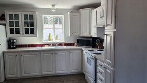 A kitchen with white cabinets, a microwave, a stove, and a sink.