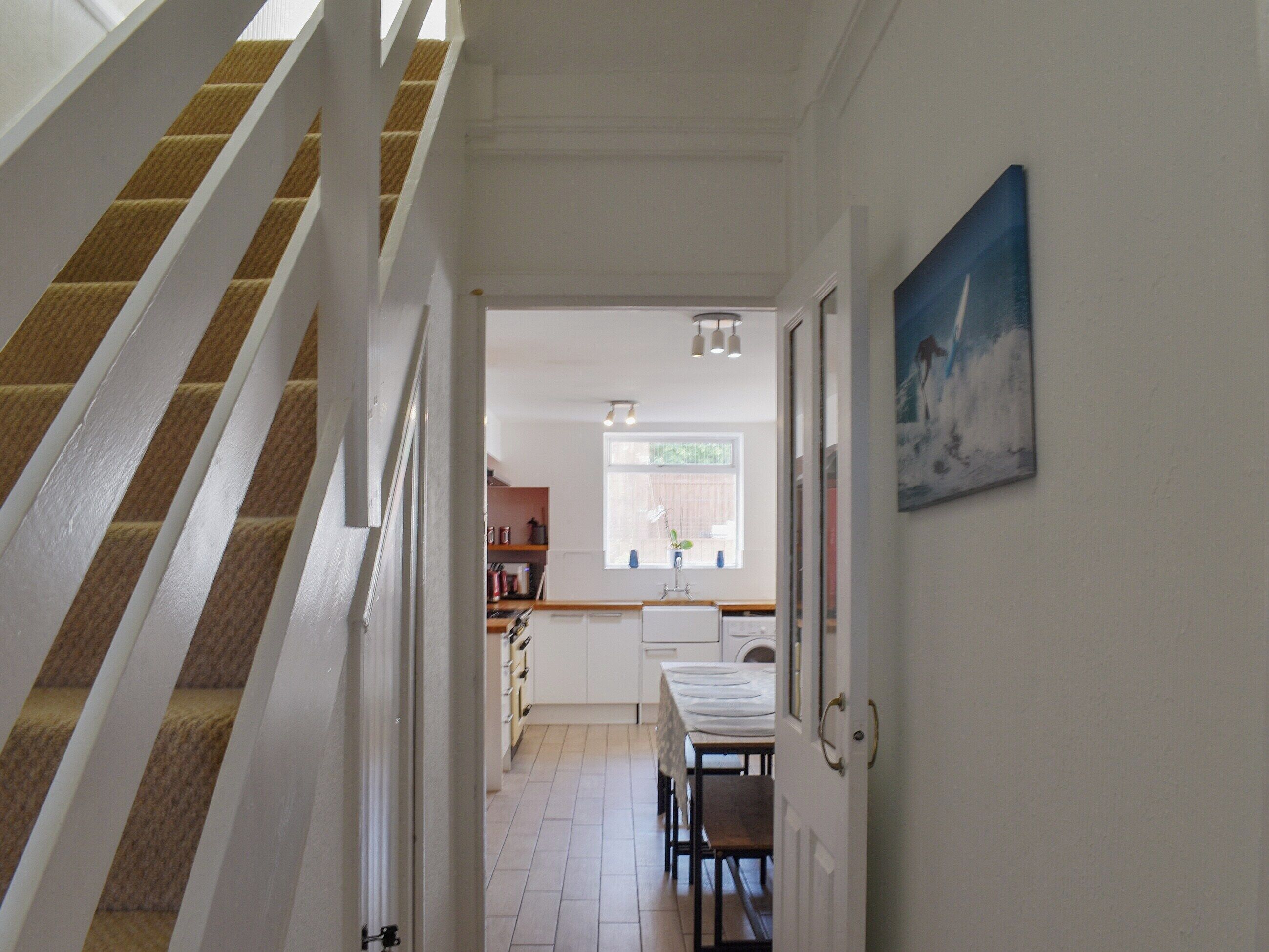 Una escalera conduce a una cocina con una mesa y sillas para comer.