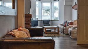 A living room with a leather sofa, a wooden coffee table, a TV, and a fireplace. - A spacious town house, with lots of character. (Newquay)