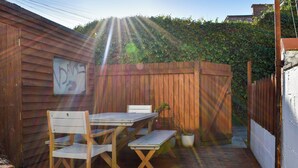A wooden deck with a table and chairs, a potted plant, and a wooden fence. - A spacious town house, with lots of character. (Newquay)