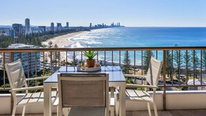 Un balcon avec une table et des chaises, offrant une vue sur la plage et le panorama de la ville.