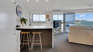 Une cuisine moderne avec un coin bar, une grande fenêtre donnant sur la ville et un espace salon confortable avec vue.