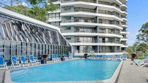 Un hôtel moderne doté d’une piscine sur le toit, de nombreux balcons et d’une façade en verre.