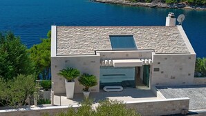 Un bâtiment moderne avec une façade en pierre, un petit balcon et un espace piscine.