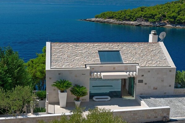 A modern building with a stone facade, a small balcony, and a pool area.