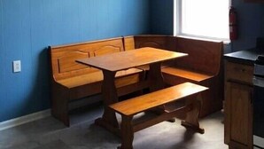 Ein Zimmer mit einer hölzernen Bank und einem Tisch, einem Fenster und blauen Wänden.