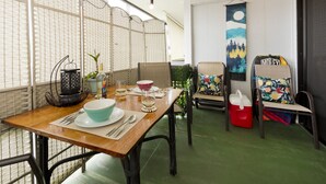 A dining area with a wooden table set for two, a decorative lantern, and a view of the outside through a partition. - Happy Honu Oasis, Surf shack with pool and A/C (Hilo)