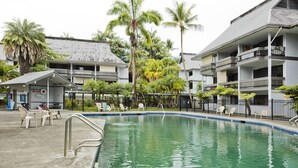A swimming pool with lounge chairs, a small building labeled "HOTEL," and palm trees. - Happy Honu Oasis, Surf shack with pool and A/C (Hilo)