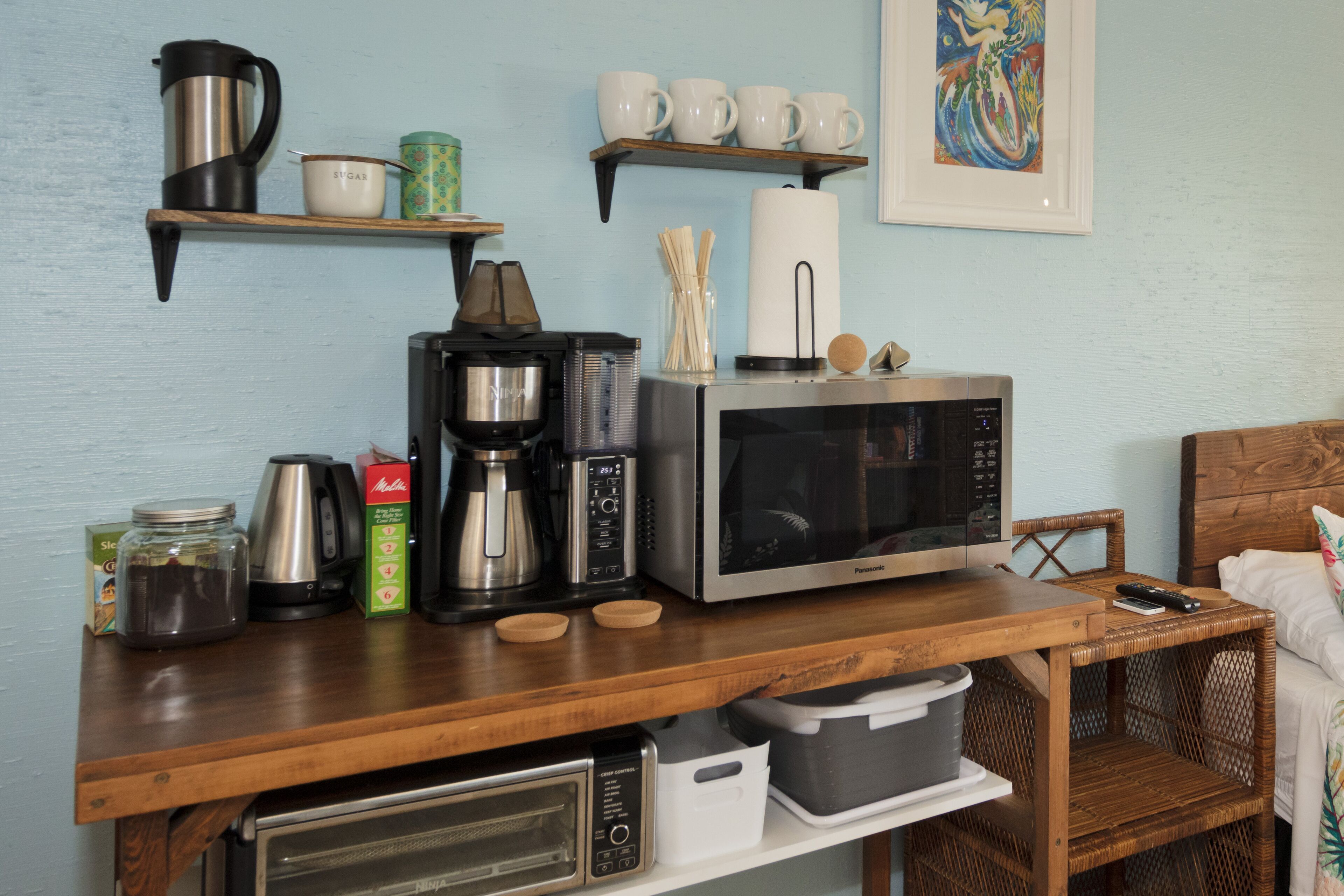 Una encimera de cocina con cafetera, microondas, tostadora y diversos utensilios de cocina.